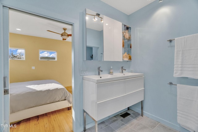 bathroom with baseboards, double vanity, ceiling fan, and wood finished floors