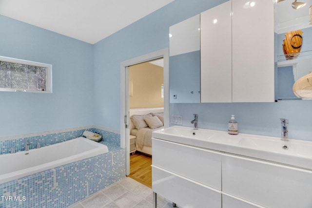 ensuite bathroom featuring a bath, double vanity, a sink, and ensuite bath