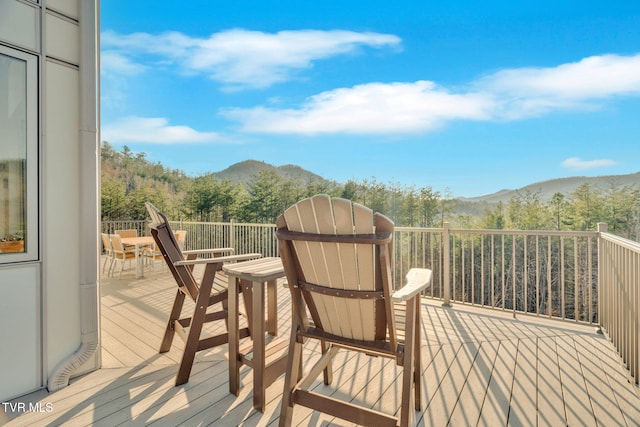 wooden deck with a mountain view and a view of trees