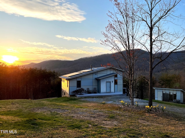 view of home's exterior with dirt driveway, a mountain view, and a yard