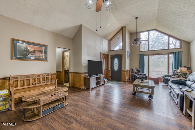 living area with a ceiling fan, dark wood finished floors, a textured ceiling, and wainscoting