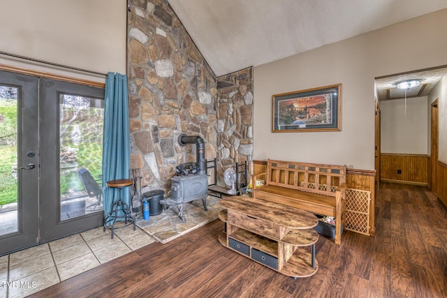 living area featuring a wood stove, wood finished floors, french doors, and wainscoting