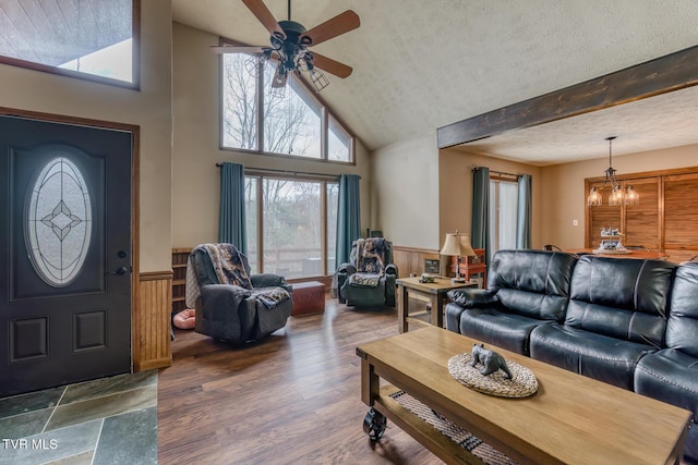 living room with a wainscoted wall, wood finished floors, ceiling fan with notable chandelier, and a textured ceiling