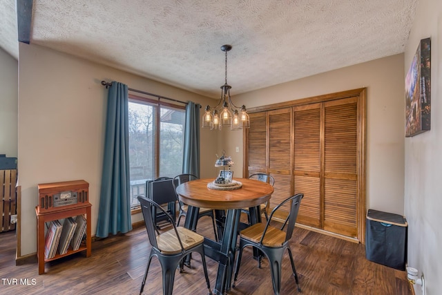 dining space with dark wood-style floors, a notable chandelier, and a textured ceiling