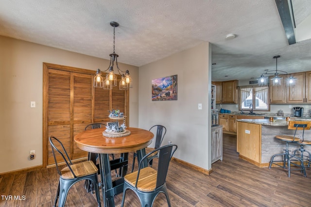 dining space with a textured ceiling, baseboards, and dark wood finished floors