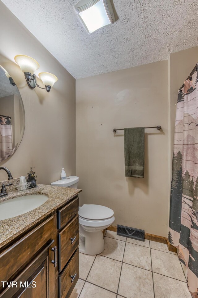full bath with a textured ceiling, visible vents, toilet, vanity, and tile patterned flooring
