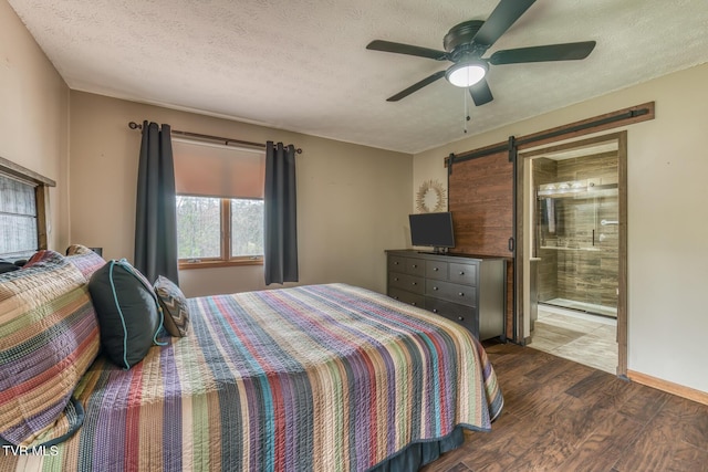 bedroom with a textured ceiling, connected bathroom, a barn door, ceiling fan, and wood finished floors