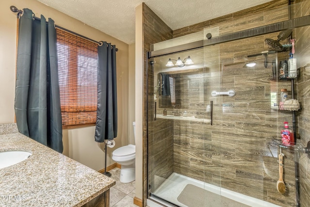 bathroom with tile patterned flooring, vanity, toilet, a textured ceiling, and a stall shower