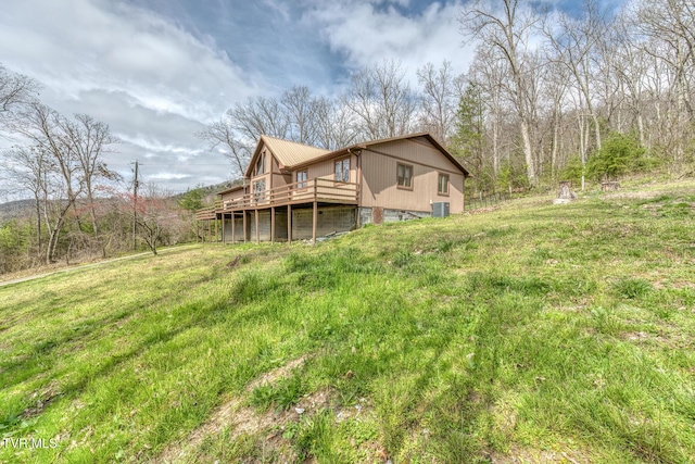 rear view of house featuring a wooden deck and a yard