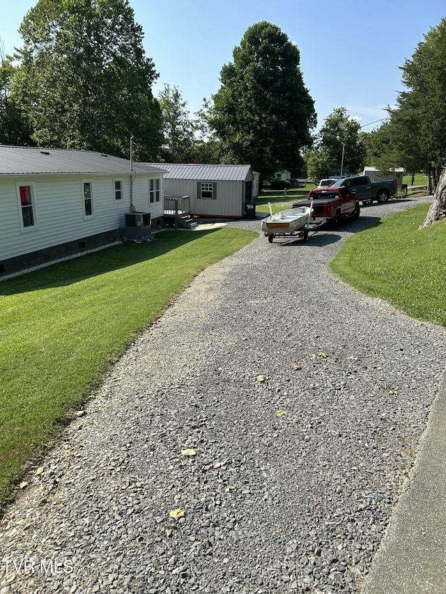 exterior space featuring a front lawn, driveway, and cooling unit