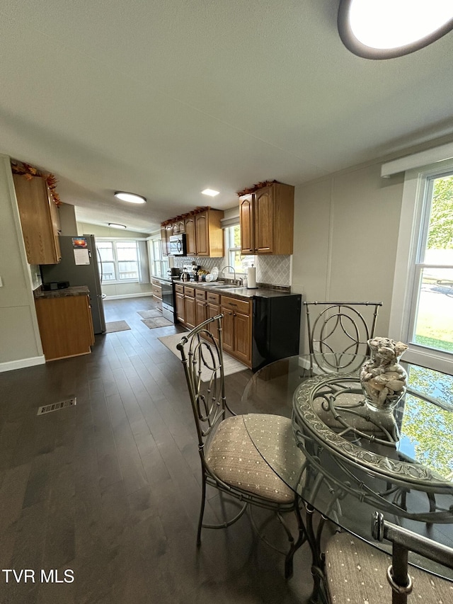 dining space featuring dark wood-style flooring, visible vents, baseboards, and a wealth of natural light