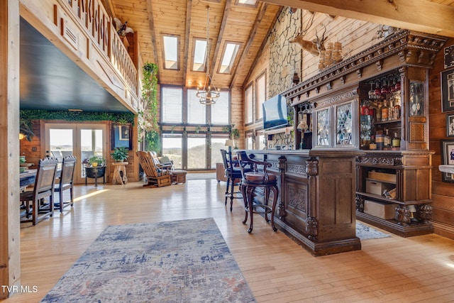 bar with hardwood / wood-style floors, high vaulted ceiling, wood ceiling, a bar, and a notable chandelier