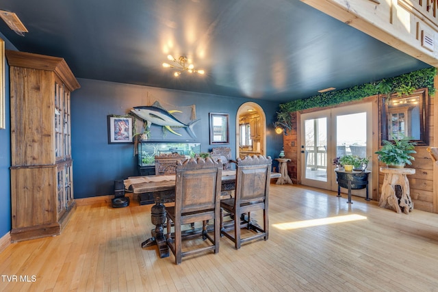 dining room with baseboards, arched walkways, and light wood-style floors