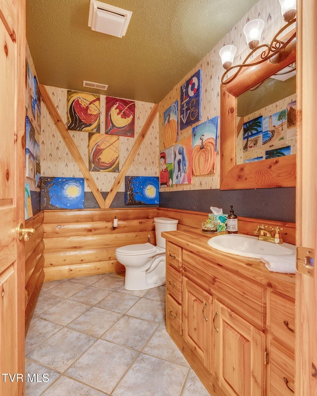 bathroom featuring vanity, toilet, log walls, a textured ceiling, and visible vents