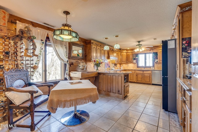 kitchen with visible vents, a peninsula, ceiling fan, stainless steel dishwasher, and brown cabinetry
