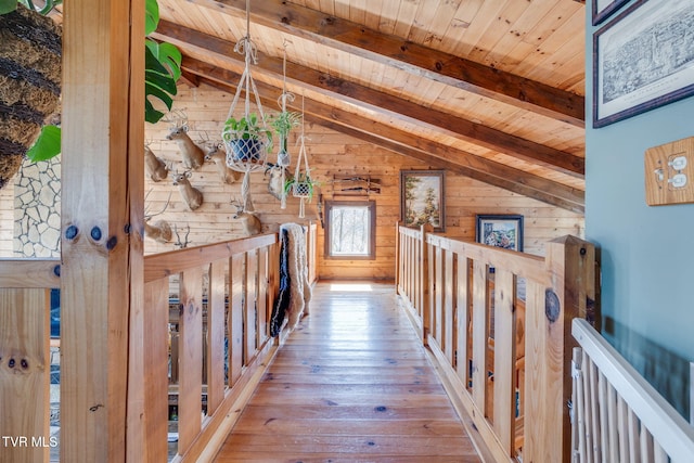 corridor with wooden ceiling, an upstairs landing, lofted ceiling with beams, wooden walls, and hardwood / wood-style floors
