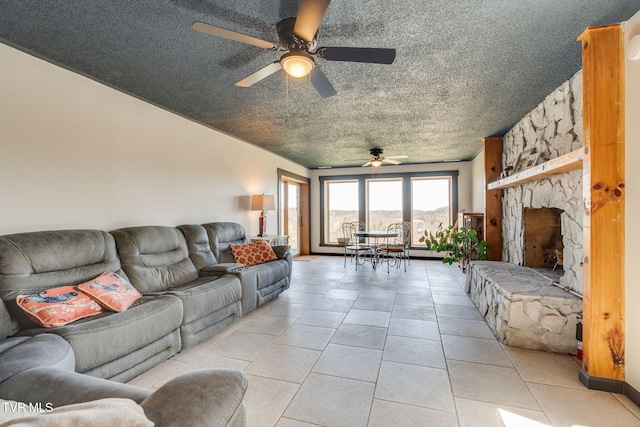 living room with light tile patterned flooring, a stone fireplace, a textured ceiling, and ceiling fan