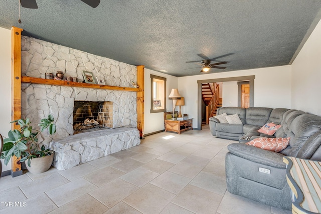 living area with stairway, a fireplace, a textured ceiling, baseboards, and ceiling fan