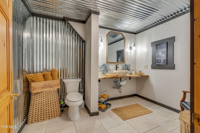bathroom with baseboards, toilet, and tile patterned flooring