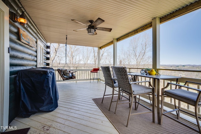 wooden deck with outdoor dining area and a ceiling fan