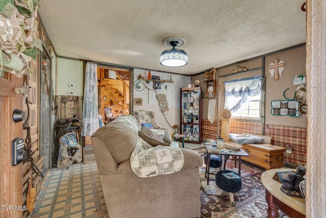 living area featuring wainscoting, tile patterned floors, and a textured ceiling