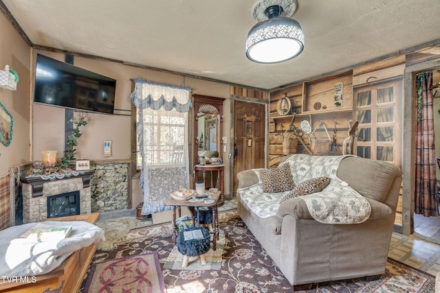 living area featuring a stone fireplace and a textured ceiling