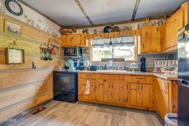 kitchen featuring light countertops, stainless steel appliances, a sink, light wood finished floors, and brown cabinets