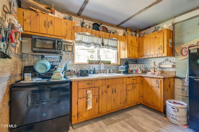 kitchen with a sink, light countertops, black appliances, and brown cabinets