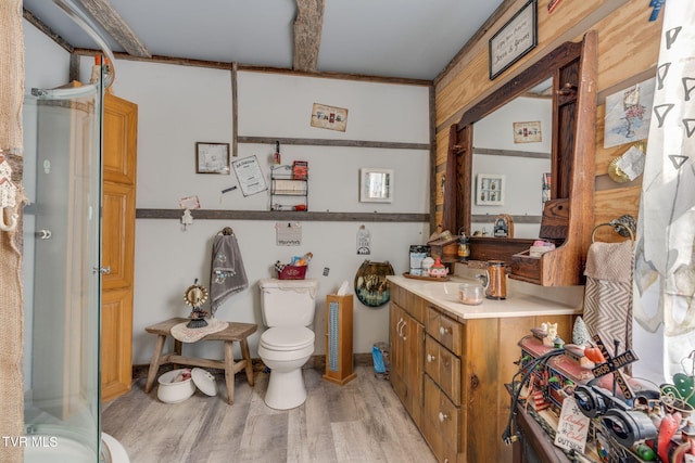 full bath with a shower with door, toilet, wood finished floors, and vanity
