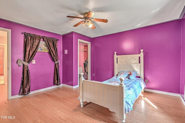 bedroom with baseboards, a textured ceiling, ceiling fan, and wood finished floors