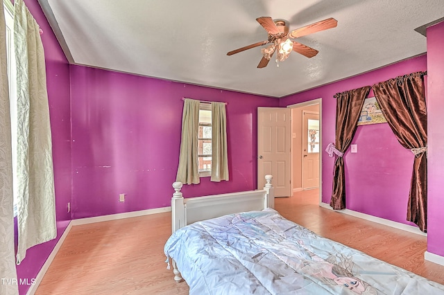 bedroom with baseboards, a ceiling fan, wood finished floors, and a textured ceiling