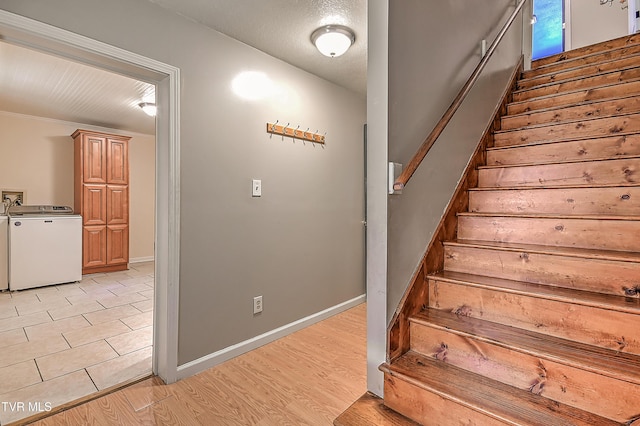 stairway featuring baseboards, wood finished floors, and washing machine and clothes dryer