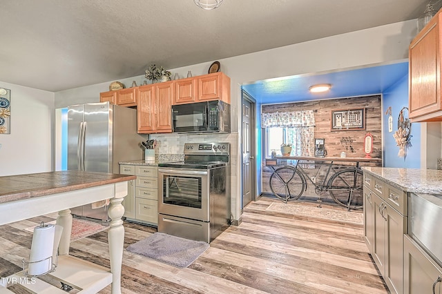 kitchen with decorative backsplash, a textured ceiling, light wood-style floors, and appliances with stainless steel finishes