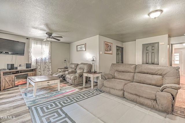 living room with plenty of natural light, a textured ceiling, light wood finished floors, and ceiling fan