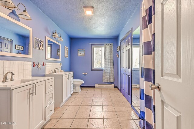 full bathroom featuring toilet, backsplash, a sink, baseboard heating, and tile patterned flooring