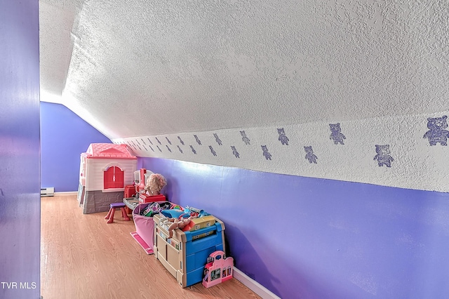 rec room with a textured ceiling, baseboards, vaulted ceiling, and wood finished floors