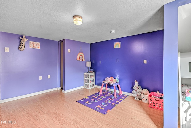 rec room with baseboards, wood finished floors, and a textured ceiling