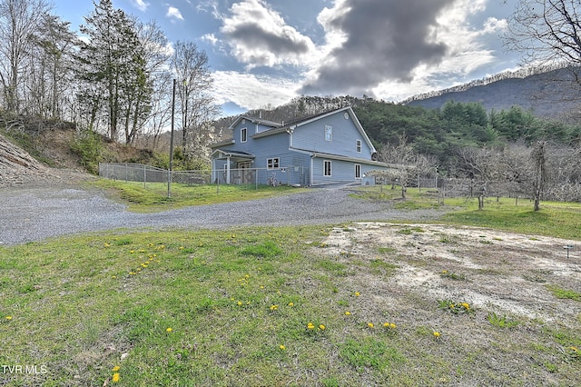 view of side of home with a lawn and fence