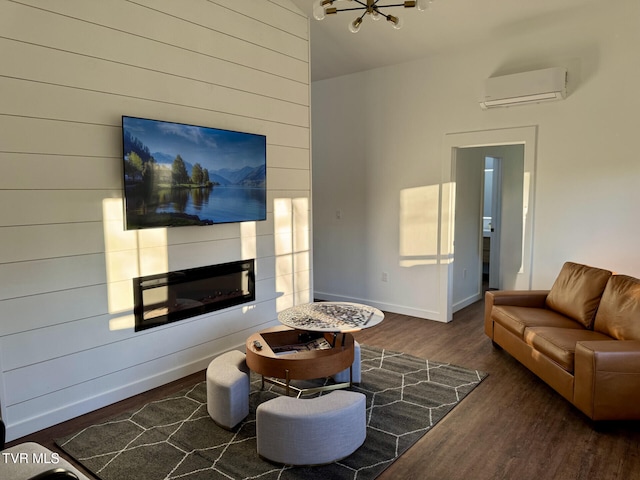living area with a wall mounted AC, wooden walls, baseboards, wood finished floors, and a notable chandelier