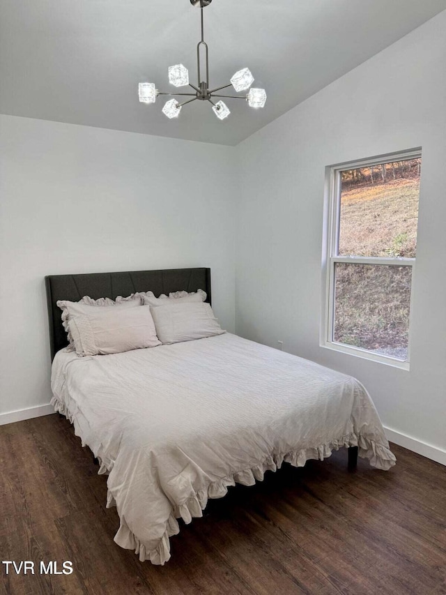 bedroom with a notable chandelier, baseboards, lofted ceiling, and wood finished floors