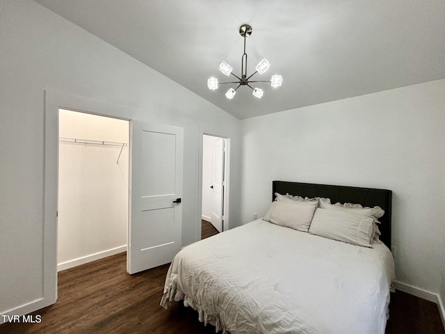 bedroom featuring a notable chandelier, vaulted ceiling, a spacious closet, dark wood finished floors, and baseboards