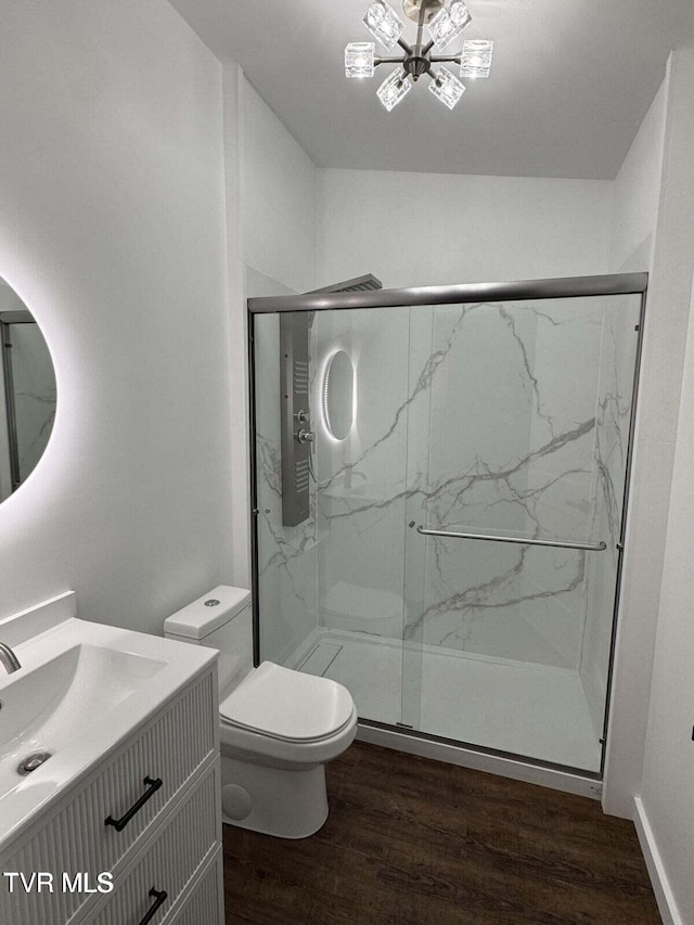 bathroom with vanity, a marble finish shower, an inviting chandelier, toilet, and wood finished floors