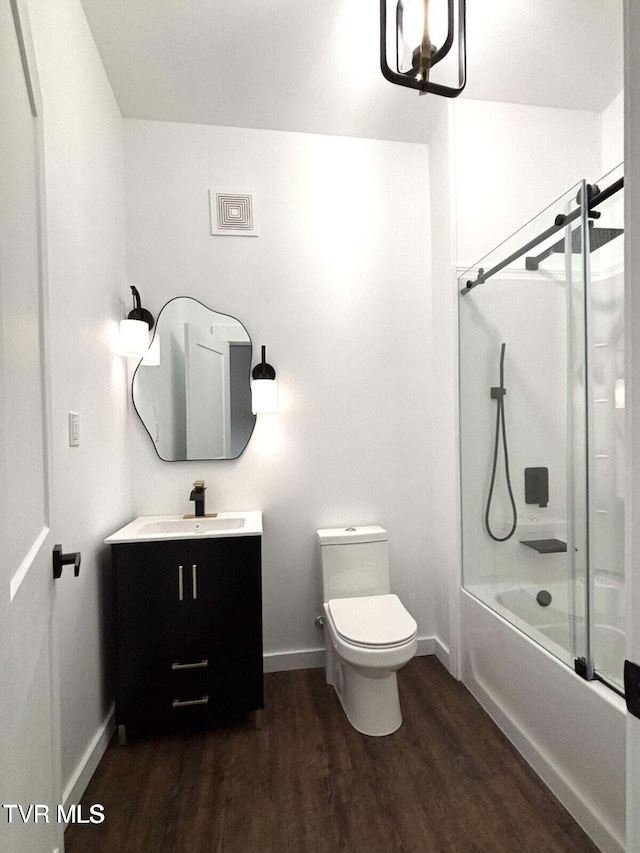 bathroom with vanity, toilet, baseboards, combined bath / shower with glass door, and wood finished floors