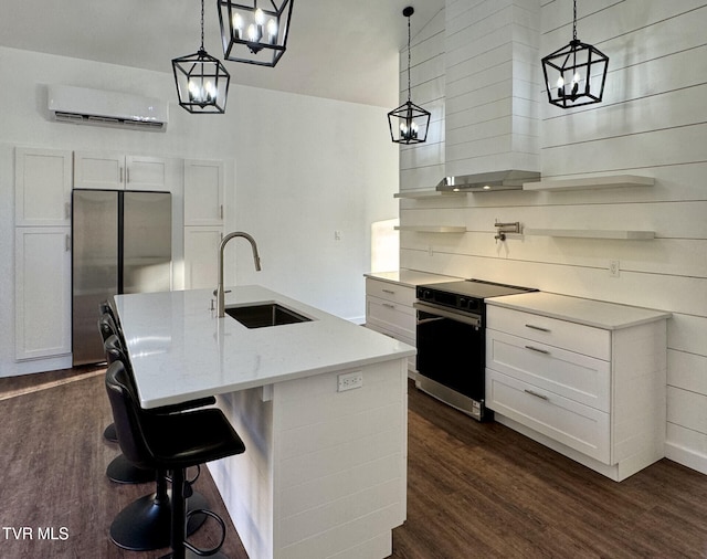 kitchen with a wall mounted AC, an inviting chandelier, stainless steel appliances, a sink, and dark wood-style floors