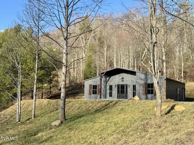 exterior space featuring an outbuilding, a view of trees, an outdoor structure, and board and batten siding