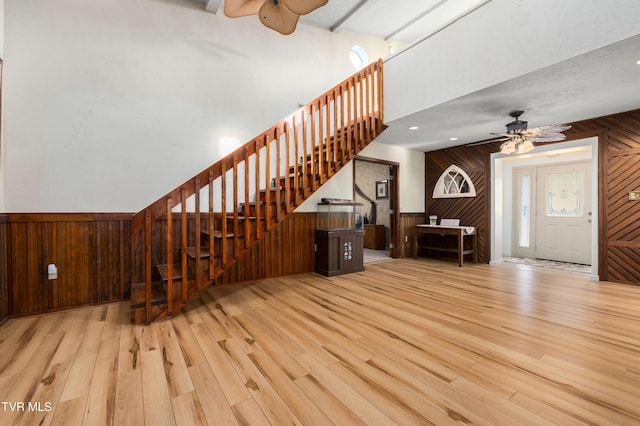 166 Lonesome Dove Ln, Elizabethton, TN 37643 - unfurnished living room featuring a ceiling fan, wooden walls, wainscoting, wood finished floors, and stairs