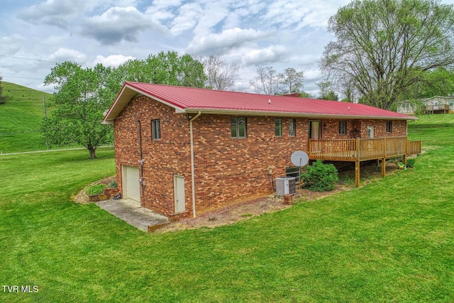 rear view of house with a wooden deck, a yard, brick siding, and a garage
