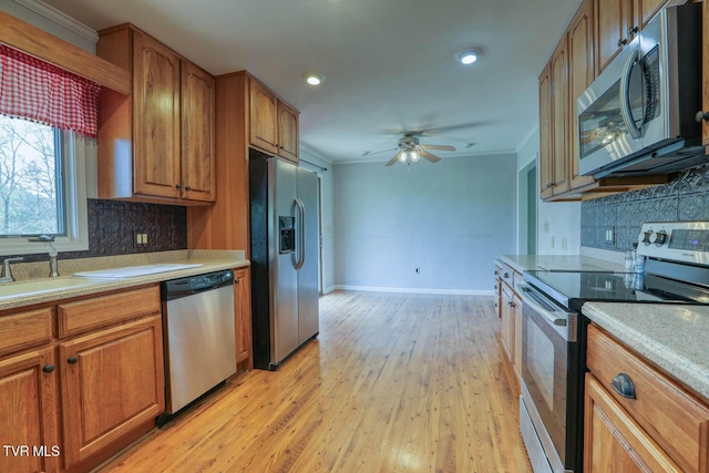 kitchen with crown molding, stainless steel appliances, light countertops, a ceiling fan, and brown cabinetry