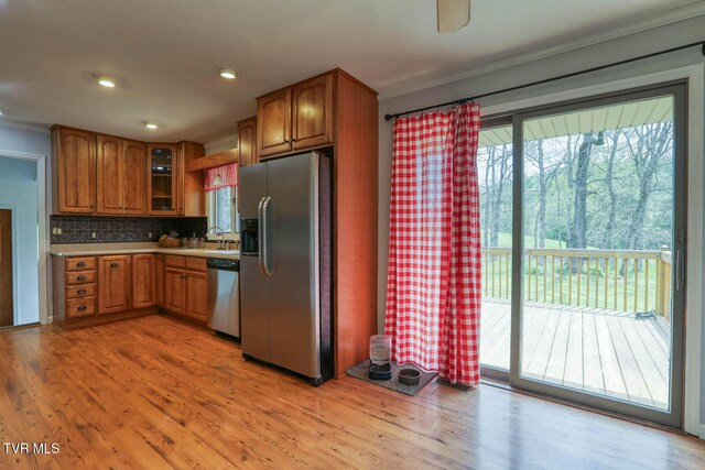 kitchen with crown molding, brown cabinets, appliances with stainless steel finishes, and plenty of natural light