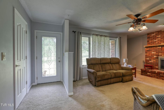 living area with a textured ceiling, baseboards, light carpet, a fireplace, and a ceiling fan